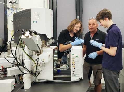 Armin Kriele (middle) has offered internships for interested high school students for several years, here at the scanning elelectron microscope of the materials science lab. 